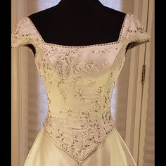 a white wedding dress on display in front of a door with a black mannequin