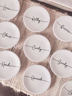 six white plates with names on them sitting next to each other