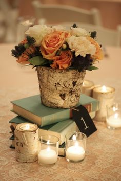 a table topped with books and candles next to flowers in a vase on top of each other