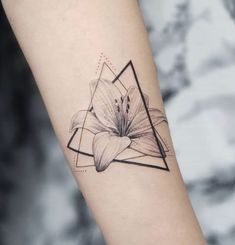 a black and white photo of a flower tattoo on the left inner arm, with an inverted triangle behind it