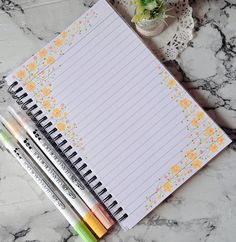 three pencils sitting on top of a notepad next to a potted plant