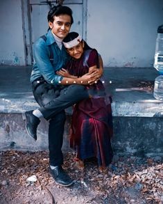 a man and woman are sitting on the steps outside their house, hugging each other