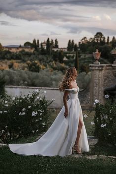 a woman in a wedding dress standing on the grass