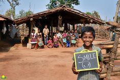 a young boy holding up a chalkboard with the word smile on it in front of a group of people