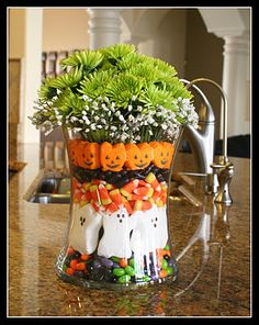 a glass vase filled with candy and halloween decorations on top of a kitchen counter next to a sink