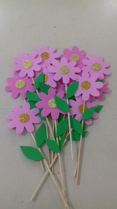 pink flowers with green leaves and gold glitters on them are arranged in a bouquet