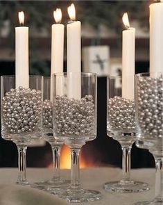 there are many candles that are in the glass vases with beads on them and one candle is lit