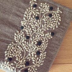 a close up of a piece of cloth on a wooden floor with white and black flowers