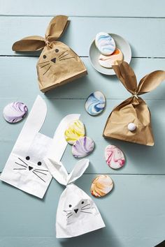 paper bags with bunny ears and marbles on the table next to them are decorated like easter bunnies