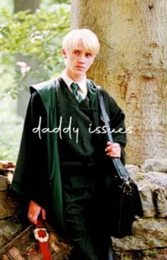 a young man dressed in a harry potter costume standing next to a tree and holding a bag