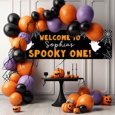 a welcome sign surrounded by balloons and pumpkins for a spooky one halloween party