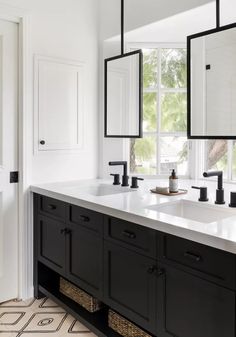 two black and white sinks in a bathroom with large mirrors on the wall above them