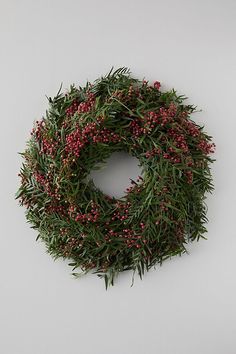 a wreath is hanging on the wall with red berries and greenery in it's center