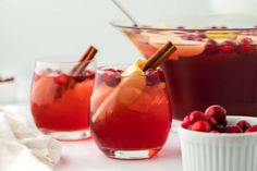 two glasses filled with cranberry punch and garnished with cinnamon sticks