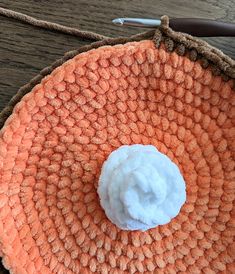 an orange crocheted basket with a white ball on it