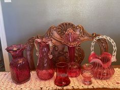 a group of red glass vases sitting on top of a table next to each other