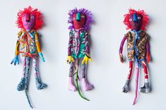 three colorful dolls are lined up on a white surface