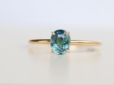 Fall in love with the simple beauty of this handmade oval shape teal sapphire solitaire ring.  The 1.04 ct center stone sparkles in the 14k yellow gold band, making it a timeless piece perfect for everyday wear or special occasions.  Available in a range of sizes and customizable to your preferences, this ring is a perfect choice for anyone who loves understated elegance and natural gemstones ◉ Setting: - Metal: 14k yellow gold - Total weight: Approx 1.4g ◉ Center Stone: - Type: Natural, Green sapphire - Shape: Oval - Weight: 1.05 cts - Color: Green - Cut Grade: Perfect - Clarity: VS - Verification certificate Available ※ BUY WITH CONFIDENCE - 14 Days Money Back Guarantee - More photos and videos can be shared upon request - Layaway payment option available - Stellar customer service - WOR Blue Oval Emerald Ring, Oval Blue Emerald Ring, Oval Sapphire Emerald Ring As Birthstone, Blue Oval Emerald Ring Fine Jewelry, Oval Sapphire Emerald Ring With Center Stone, Oval Solitaire Sapphire Ring, Blue Solitaire Emerald Ring Round Shape, Blue Solitaire Emerald Ring, Round Shape, Blue Round Solitaire Emerald Ring