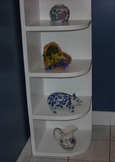 a white shelf with three different vases on it's sides and one animal figurine in the middle