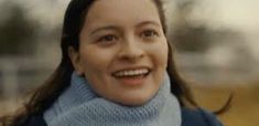 a woman smiling and wearing a blue sweater