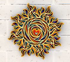 a colorful paper cut out of a sun with a heart in the center on a white brick wall