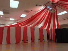 an empty room with red and white drapes on the ceiling, disco ball hanging from the ceiling