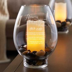 a candle that is sitting in a glass vase on a table with rocks and stones around it