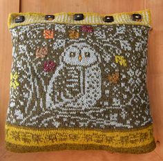 a decorative pillow with an owl design on the front and back, sitting on a wooden floor