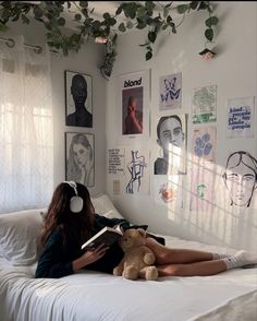 a woman laying on top of a bed holding a teddy bear and wearing headphones