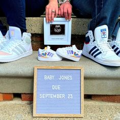 two people sitting on the steps with their adidas shoes and a sign that says baby jones due september 25