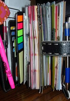 there are many different items in the holder on this desk, including pens and notebooks