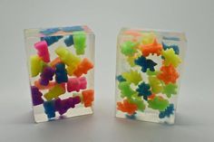 two clear boxes with multicolored gummy bears in them on a white surface