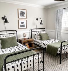 two twin beds in a bedroom with black and white bedding, green sheets and pillows