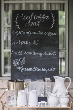 a sign that is on top of a table with cups and glasses in front of it