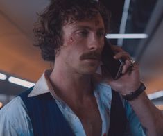 a man in suspenders talking on a cell phone