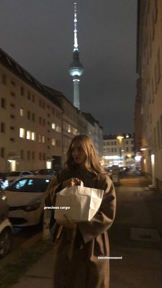 a woman is walking down the street with shopping bags in her hand and a tall building in the background