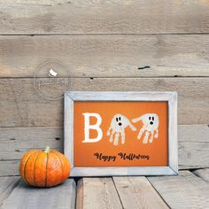 an orange pumpkin sitting on top of a wooden floor next to a sign that says boo happy halloween