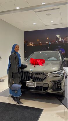 a woman standing next to a bmw car in a showroom at the dealership