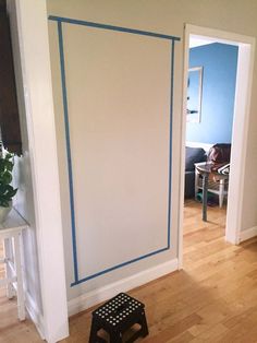 an empty room with blue tape on the walls and a step stool next to it