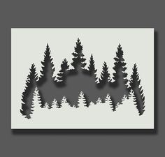 a paper cut out of trees with the shape of a house in the middle and mountains behind it