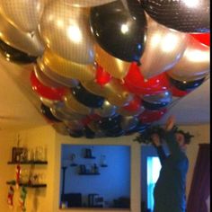 a man standing in front of a bunch of balloons hanging from the ceiling over a dining room table