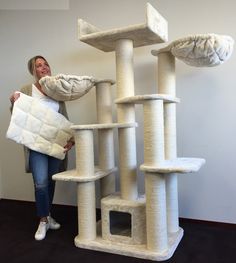 a woman standing next to a tall cat tree