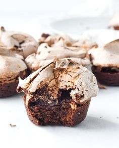 several chocolate cupcakes with white frosting on the top and one half eaten