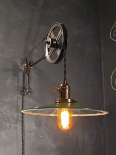 an industrial style light hanging from the side of a chalkboard wall with writing on it