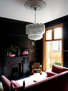 a living room filled with furniture and a chandelier hanging from the ceiling over a fire place