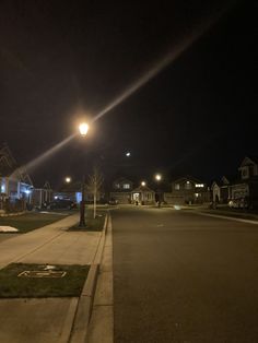 an empty street at night with lights on and houses in the backgrouds