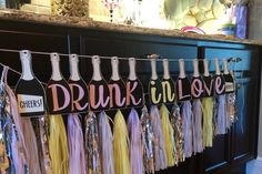 a bunch of tassels that are hanging from a bar with the words drunk and love on them