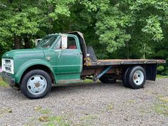 a green flatbed truck parked in front of some trees