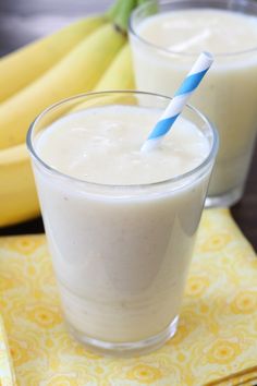 two glasses filled with milk sitting on top of a table next to banana's