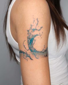 a woman's arm with a blue and white wave tattoo on her left shoulder